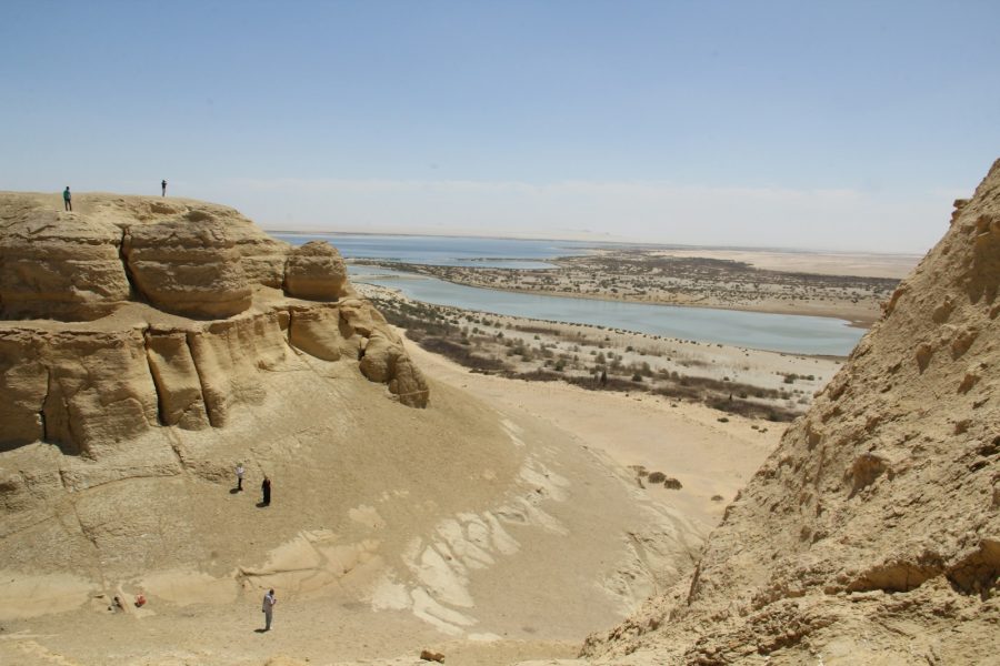 a group of people standing on top of a sandy hill